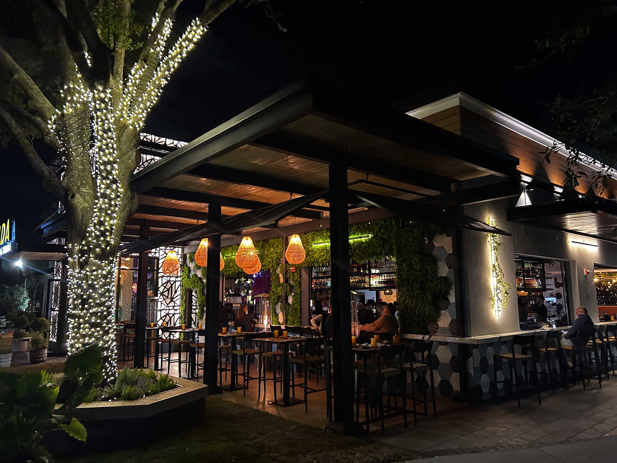 outdoor seating at night with white lights wrapped around a tree